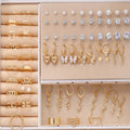 108 gold and yellow geometric alloy earrings with pearl details laid out flat.