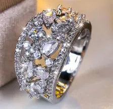 Women's round hollow copper fashion ring on a hand, showing gold and platinum finish options with blue and white accents.