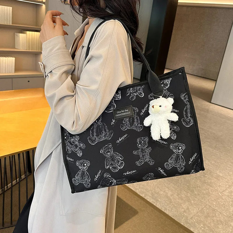 Women's black canvas tote bag with diamond pattern showing horizontal square shape and pendant attachment option