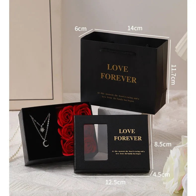 Red Valentine's gift box containing six pink soap flowers, with a matching red handbag alongside.