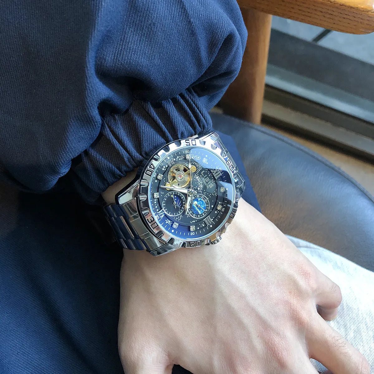 Men's silver automatic mechanical watch with black dial, luminous hands, on a black steel strap.