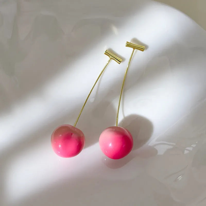 Pair of peach-shaped acrylic fashion earrings with copper posts on a white background.