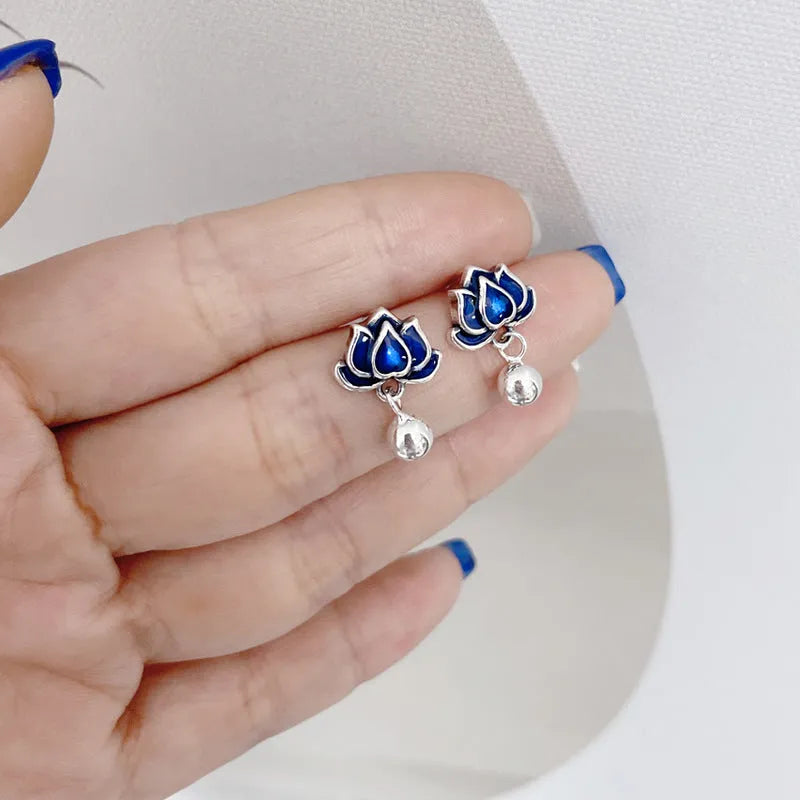 Silver-tone blue lotus flower stud earrings with a dangling seedpod tassel.