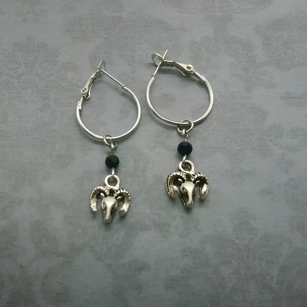 A pair of silver-coloured alloy round ring earrings with a Tibetan antelope design motif.