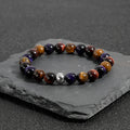 Handmade elastic tiger-eye stone bracelet showing yellow purple red colours in geometric pattern