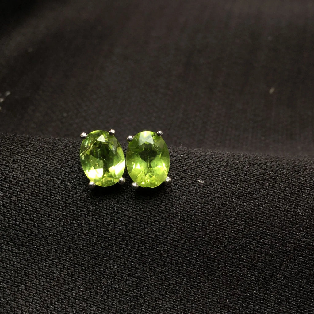 Close-up of grass green natural olivine stud earrings in S925 sterling silver setting.