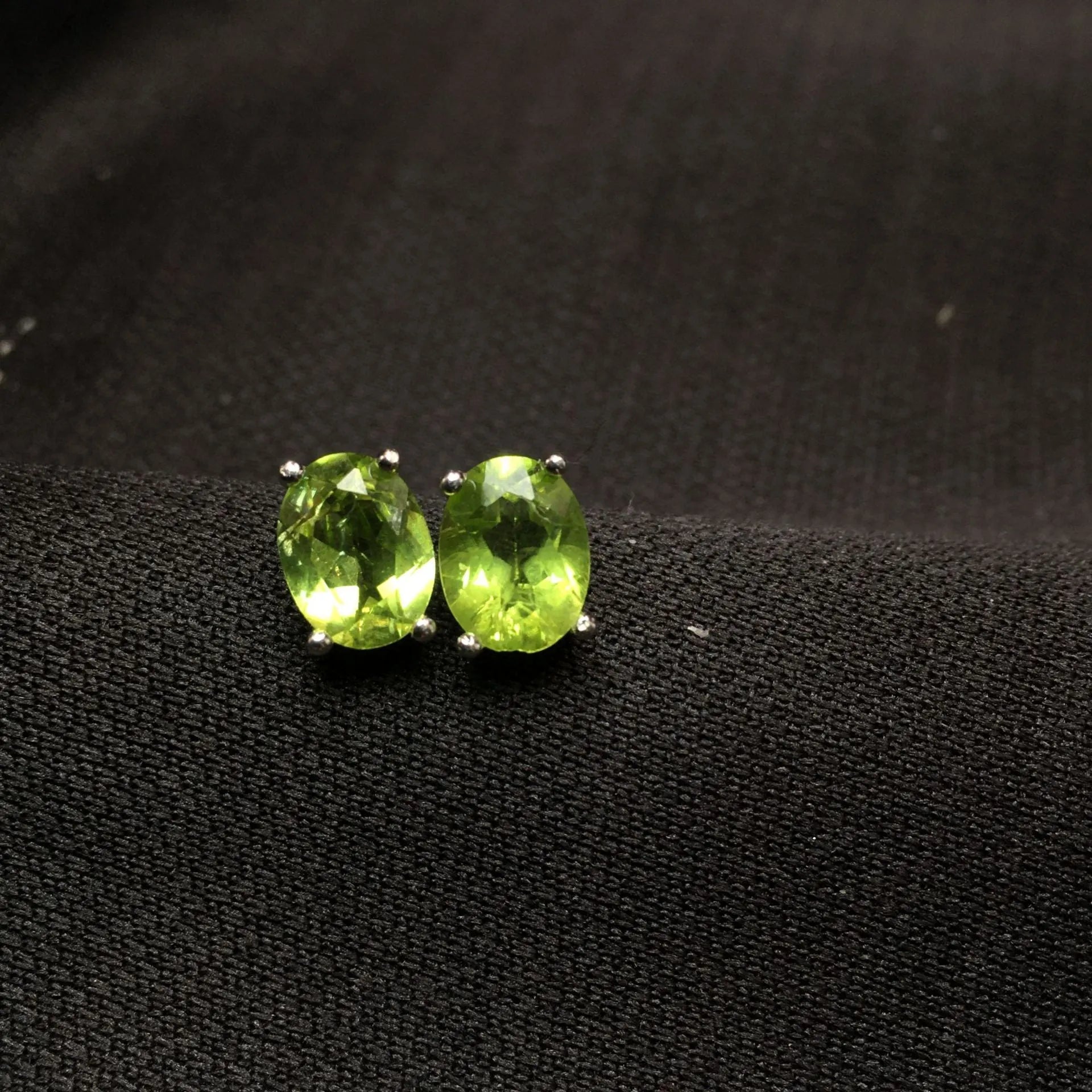 Close-up of grass green natural olivine stud earrings in S925 sterling silver setting.