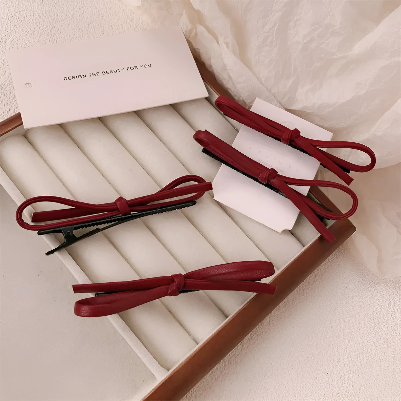 Handmade wine red leather bow hair clip on a 7cm metal alligator clip, shown on dark hair.