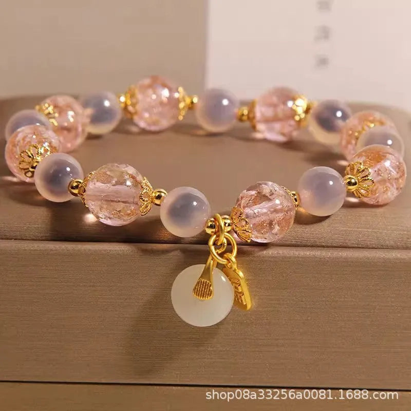 Close-up of a women's pink agate heart bracelet with a luminous glaze and a silver peace buckle clasp.