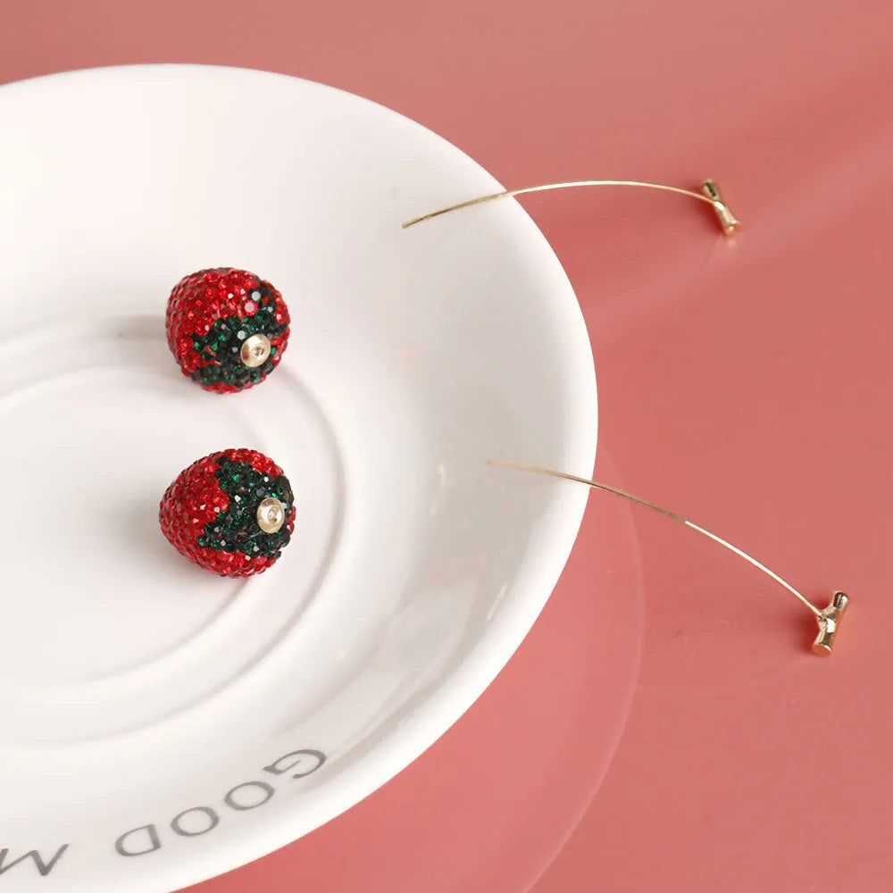 Geometric strawberry shaped zinc alloy earrings with spot drill texture on a red background.