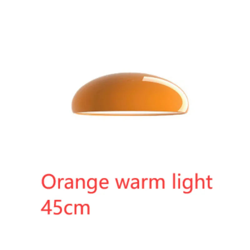 Orange iron Danish-style pendant lamp with adjustable cable above a restaurant table.