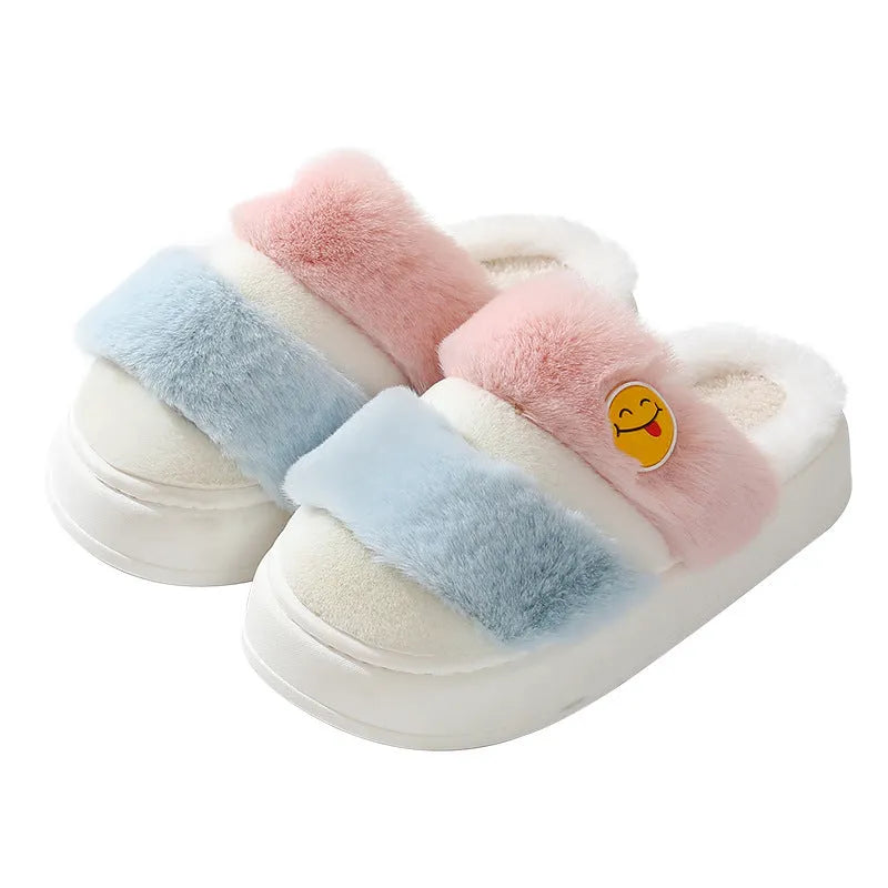 A pair of pink and green thermal plush slippers with a cashmere lining, shown on a wooden floor.