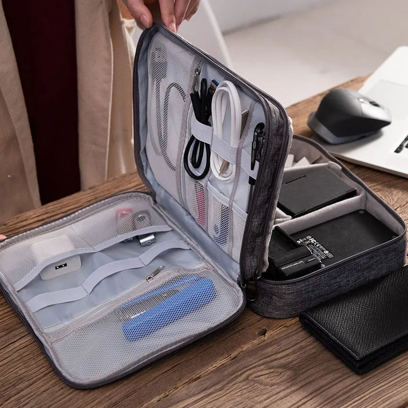 Grey waterproof electronics organiser bag with double-layer interior, handle, and zipper closure
