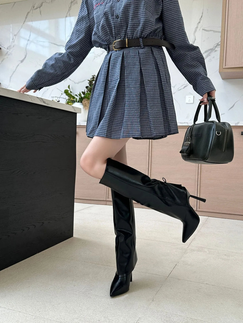 Black slip-on PU boot cover with rubber sole on a stiletto high-heel shoe.