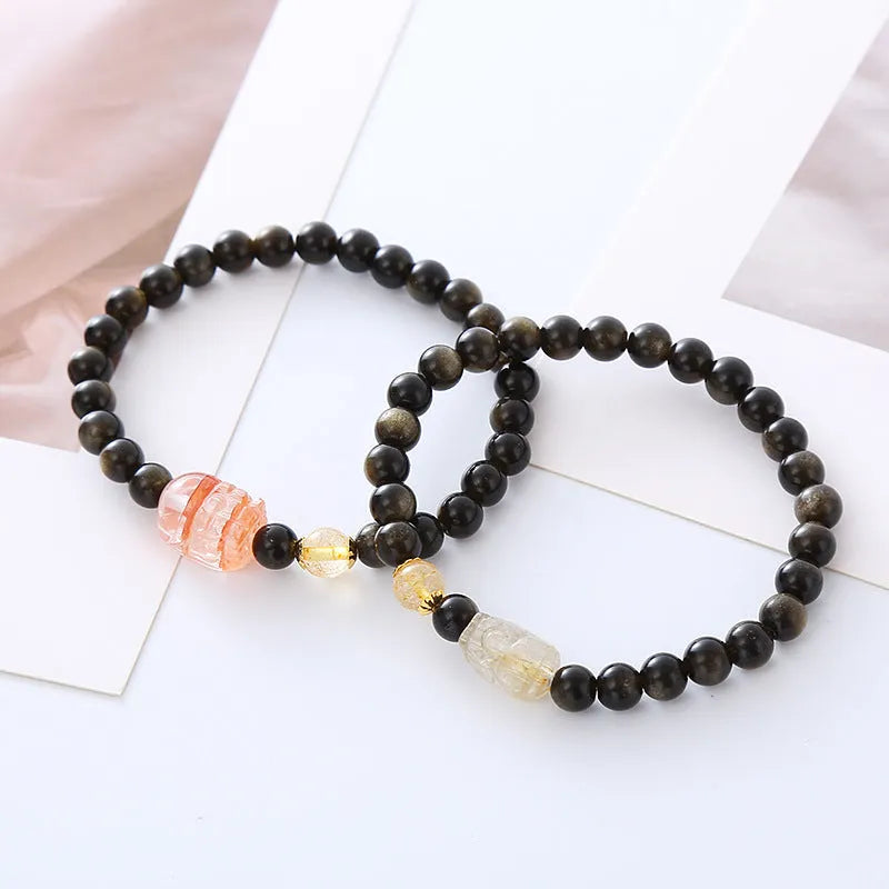 Handmade black obsidian and gold Pi Xiu charm bracelet with red flowers.