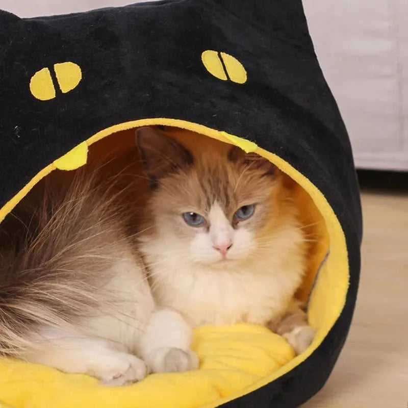 Grey cat-shaped enclosed pet bed with a round opening, sitting on a wooden floor.
