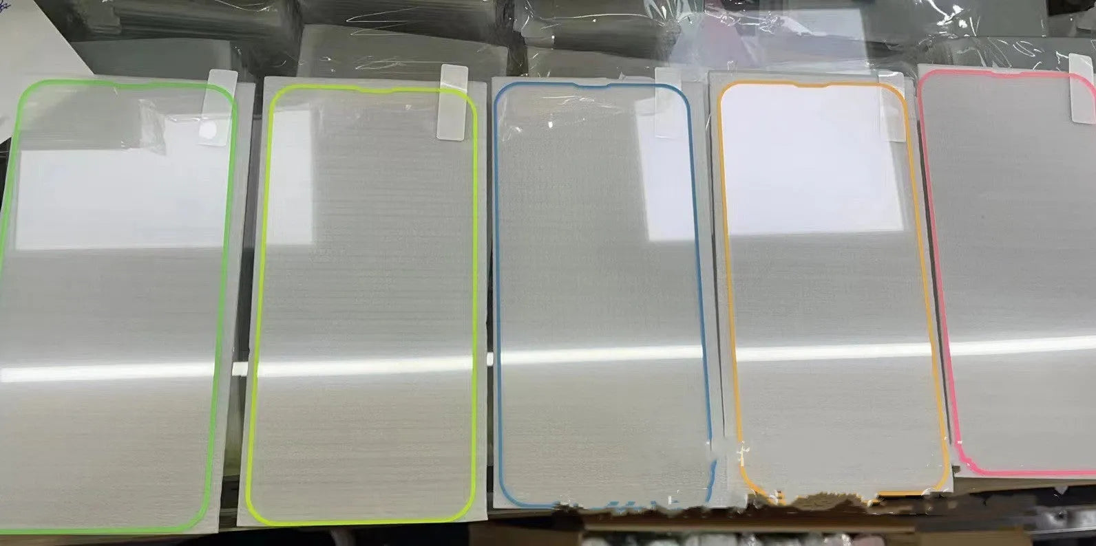 Fluorescent tempered glass screen protector glowing on an iPhone 13, showing pink luminous edge and precise camera cutout.