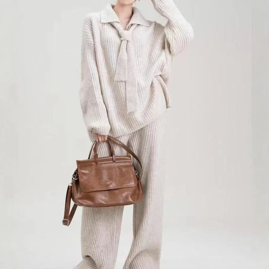Women's beige knitted two-piece suit set showing V-neck top and straight-leg trousers on a hanger.