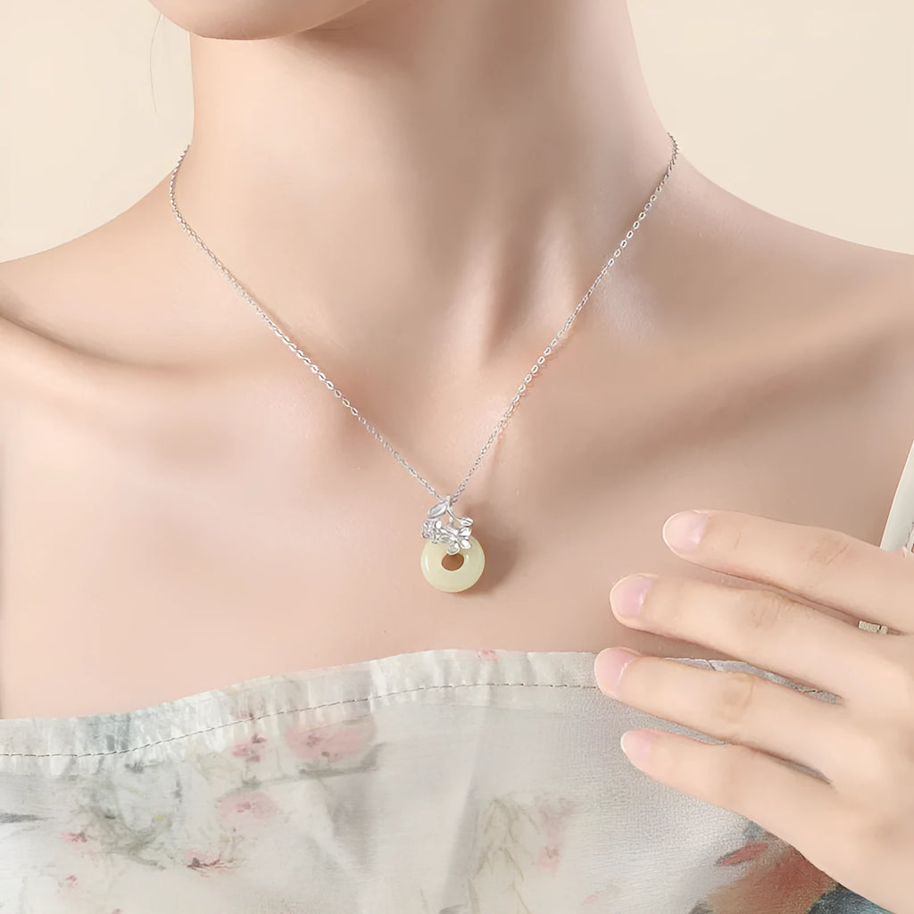 Silver pendant necklace with a peace buckle design on an adjustable cross chain.