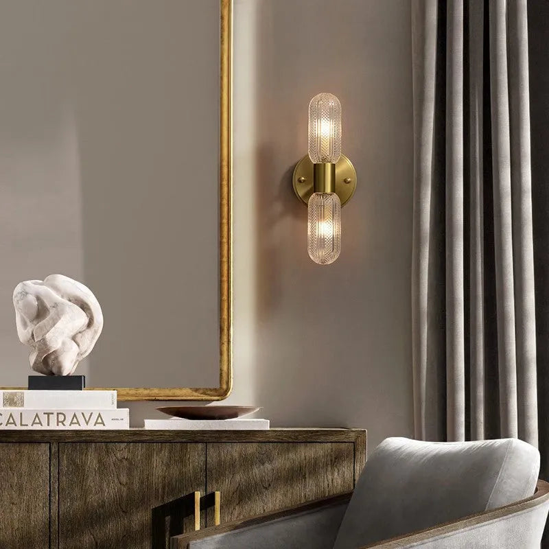 Modern double head wall lamp with a copper finish mounted on a light grey wall.