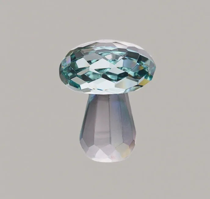 Colourful mushroom-shaped crystal decoration in geometric style on a surface, showing light green hue.