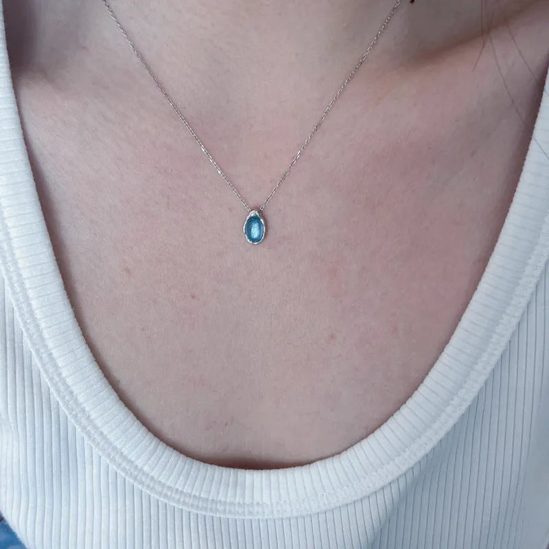 Close-up of a navy blue geometric water drop pendant on an adjustable silver-tone chain