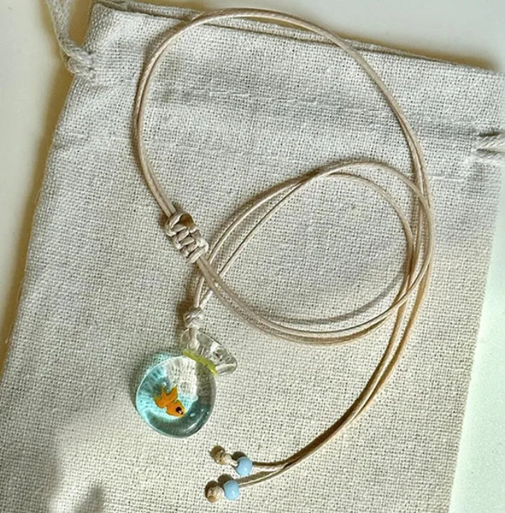 Women's joker motif pendant necklace on a braided cotton and linen clavicle chain.