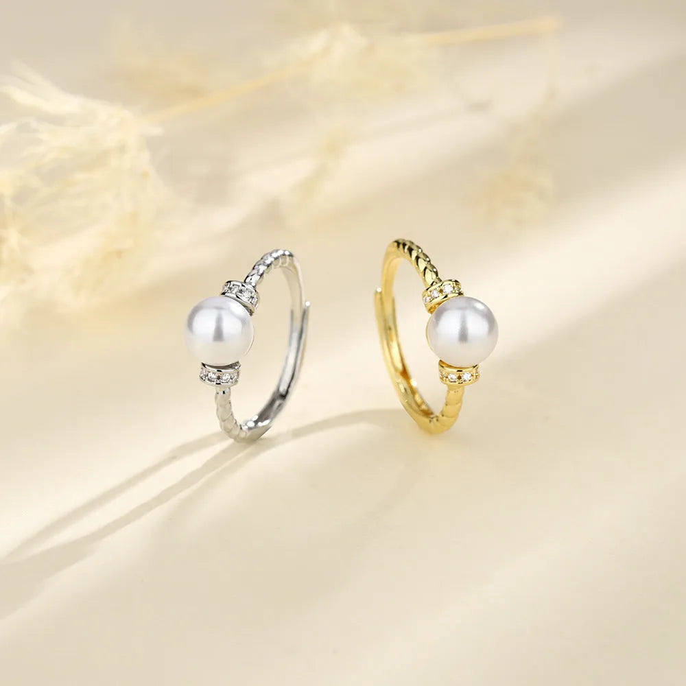 Adjustable geometric twist ring in copper with a central natural pearl on a model's finger.