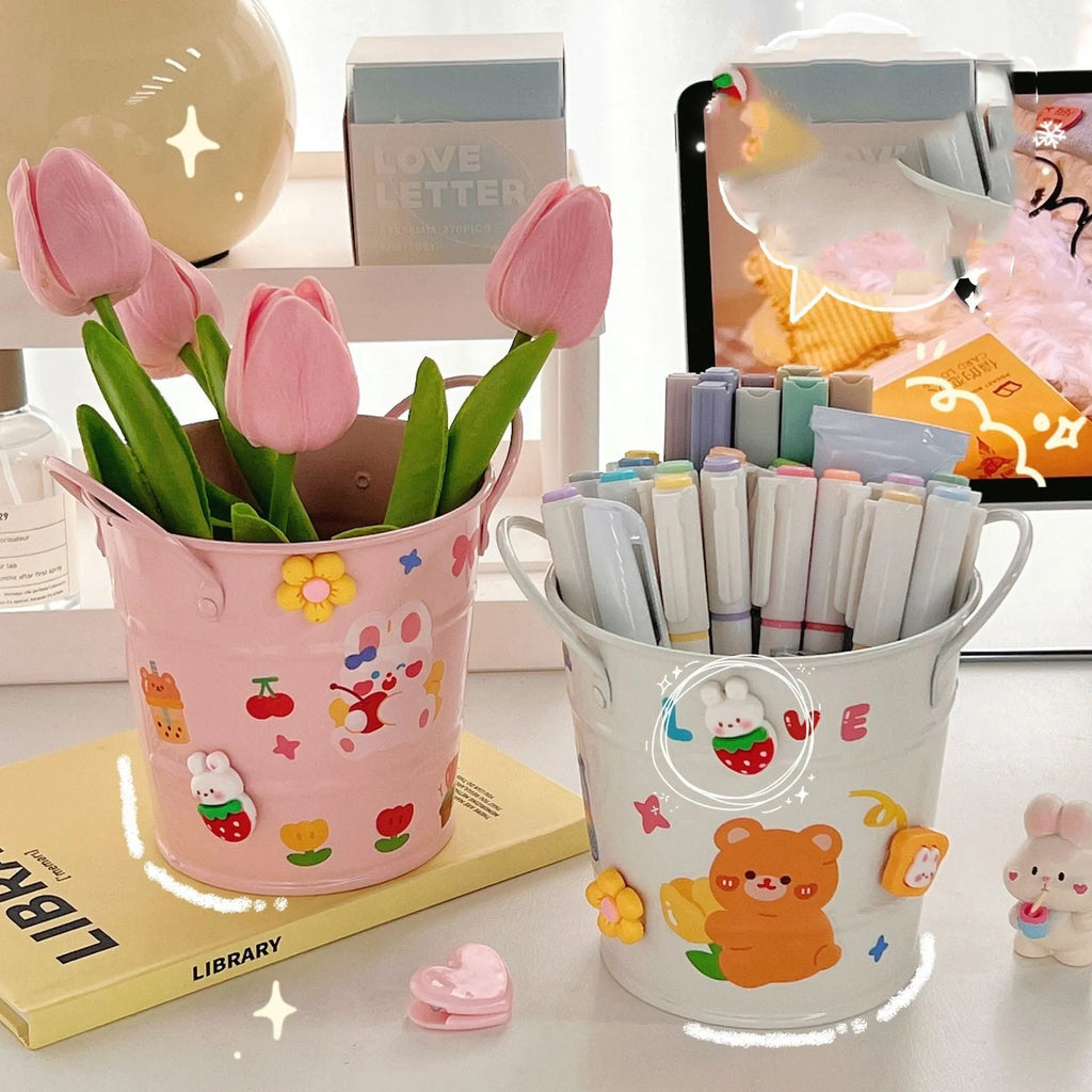 A round metal pen holder in various colours on a desk, holding pens and pencils.