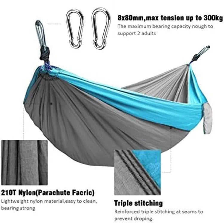 A sapphire blue parachute nylon hammock hung between two trees in a woodland setting.