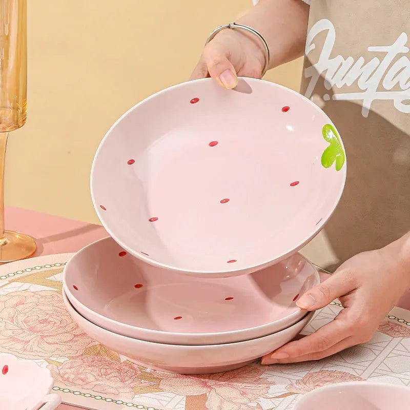 Porcelain dinnerware set with strawberry design showing bowls, plates, and a twist spoon.