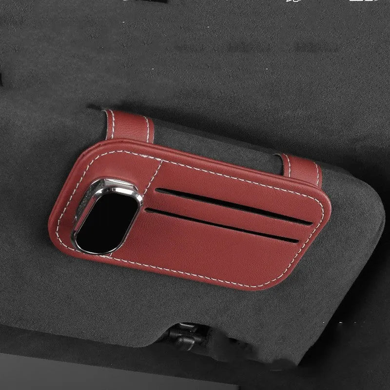 Beige cowhide automotive sun visor clip holding cards and sunglasses.