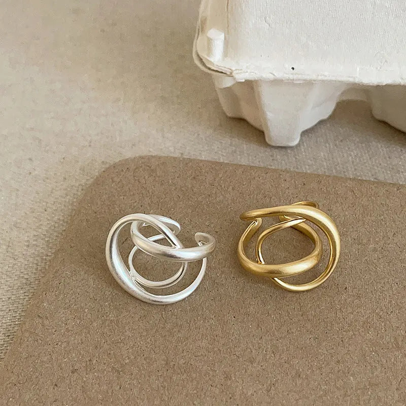 Geometric open ring with interlaced matte metal design in gold or silver plating.