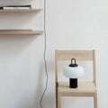 Minimalist Japanese glass bedside table lamp with warm light for a child's bedroom.
