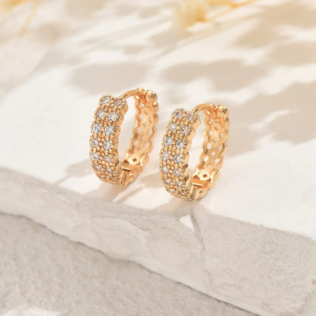 Close-up of women's copper geometric ear studs showing dot and ring pattern on a stud fitting.