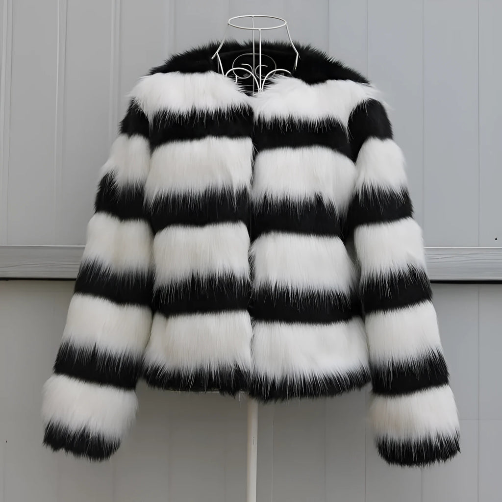 Long-sleeved black and white striped faux fur jacket for women on a grey background.