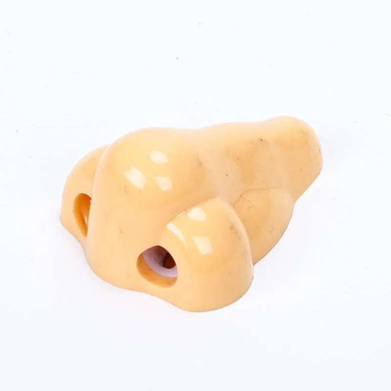 Flesh-coloured plastic manual pencil sharpener with a geometry shape, shown next to a pencil for scale.