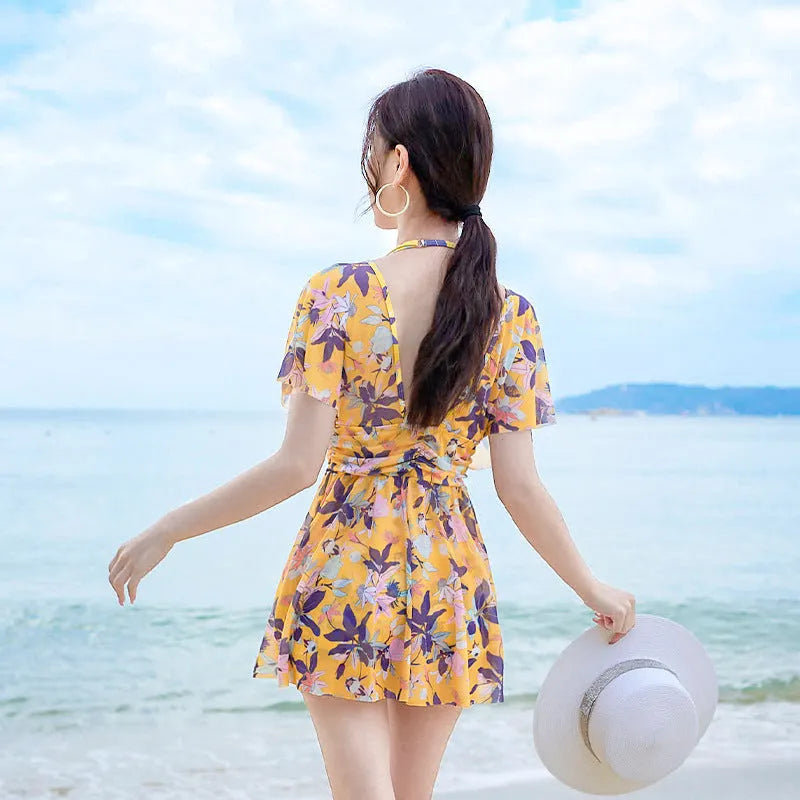 Yellow floral print women's one-piece swimsuit with skirted design.