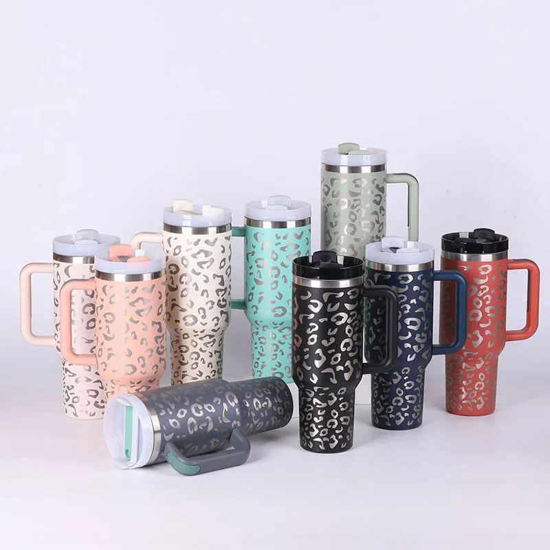 40 oz stainless steel insulated tumbler with a black handle, straw, and grey lid on a wooden table