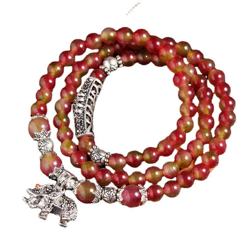 Handmade natural watermelon crystal bracelet with a Chinese knot, showing geometric beads in elephant style.