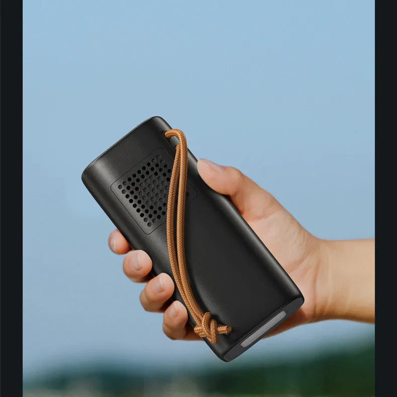 Black portable power bank with 220V socket, digital display, and solar panel on a wooden table.