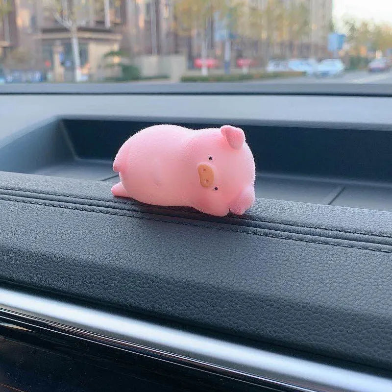 A cute cartoon pig resin figurine car decoration accessory on a dashboard.