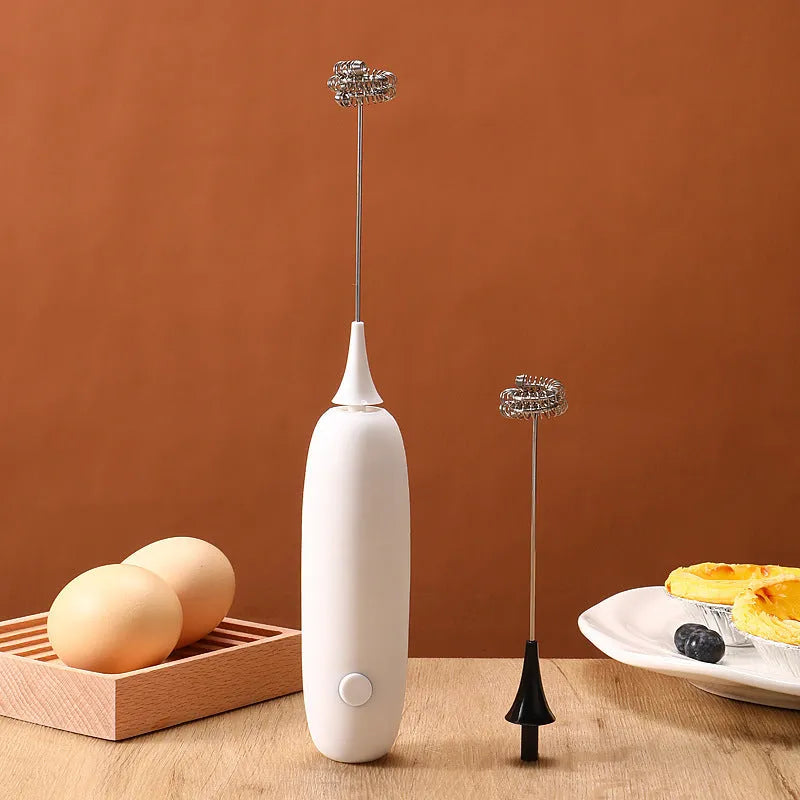 Black and white hand-held electric milk frother and blender on a kitchen counter.