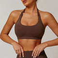 Women's halter-neck yoga bra in plum purple, showing hollow-back design and removable padding on a neutral background.