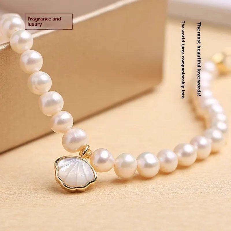 Women's freshwater pearl bracelet with a fan-shaped shell clasp on a wrist.