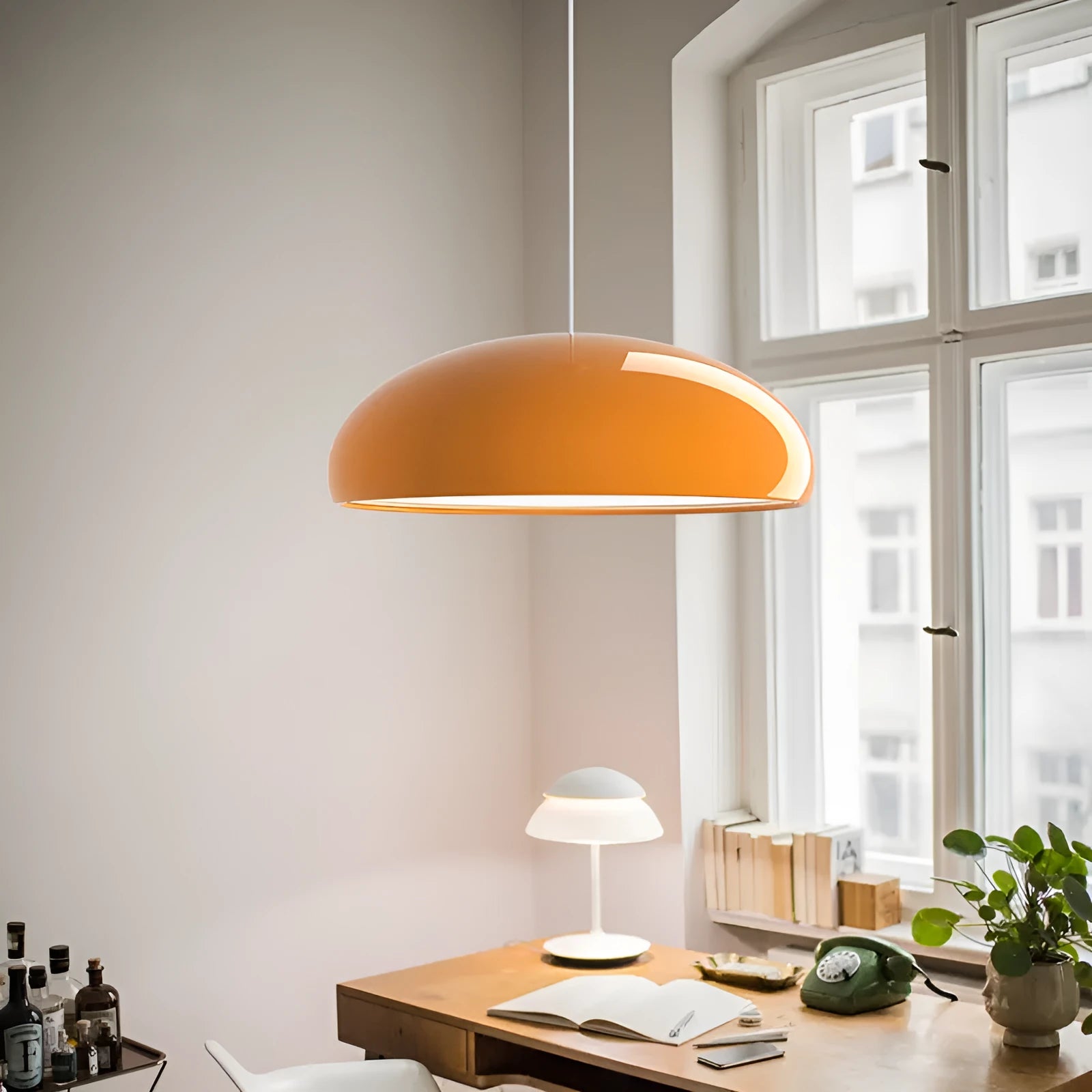 Orange iron Danish-style pendant lamp with adjustable cable above a restaurant table.