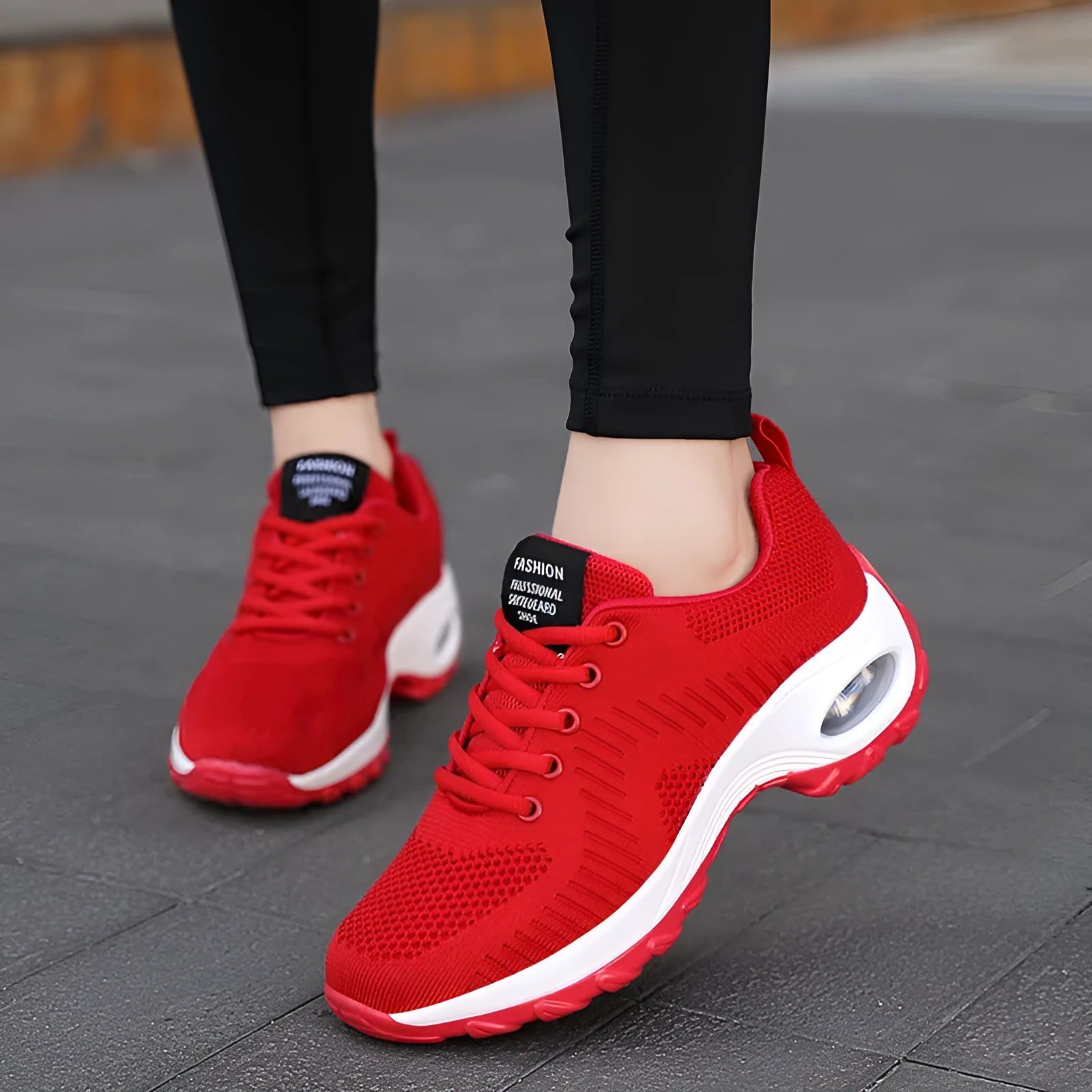 Red and black women's low-top mesh sneakers with front laces and a flat sole on a white background.