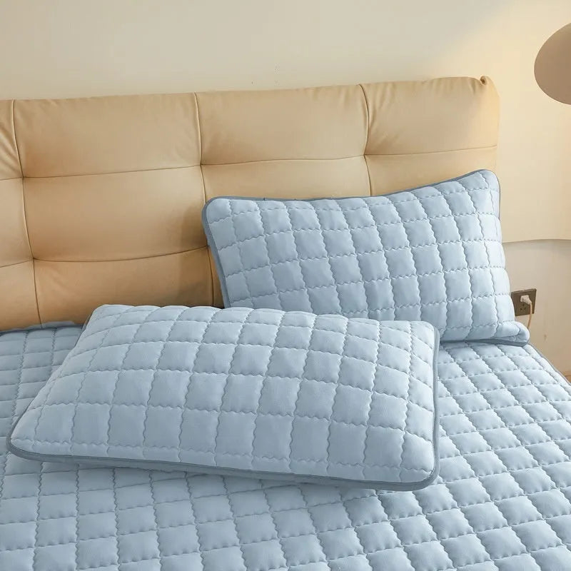 Class A waterproof fitted sheet in washed cotton, shown in a neutral colour on a bed.