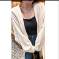 Long beige hooded knitted cardigan on a woman, showcasing its below-the-knee length and loose fit.