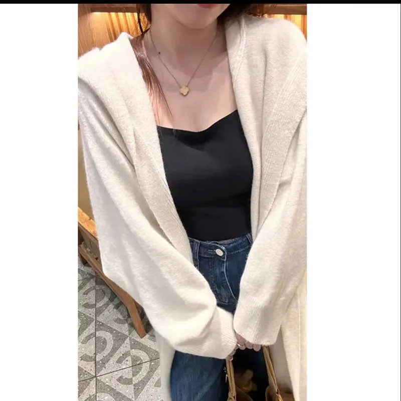 Long beige hooded knitted cardigan on a woman, showcasing its below-the-knee length and loose fit.